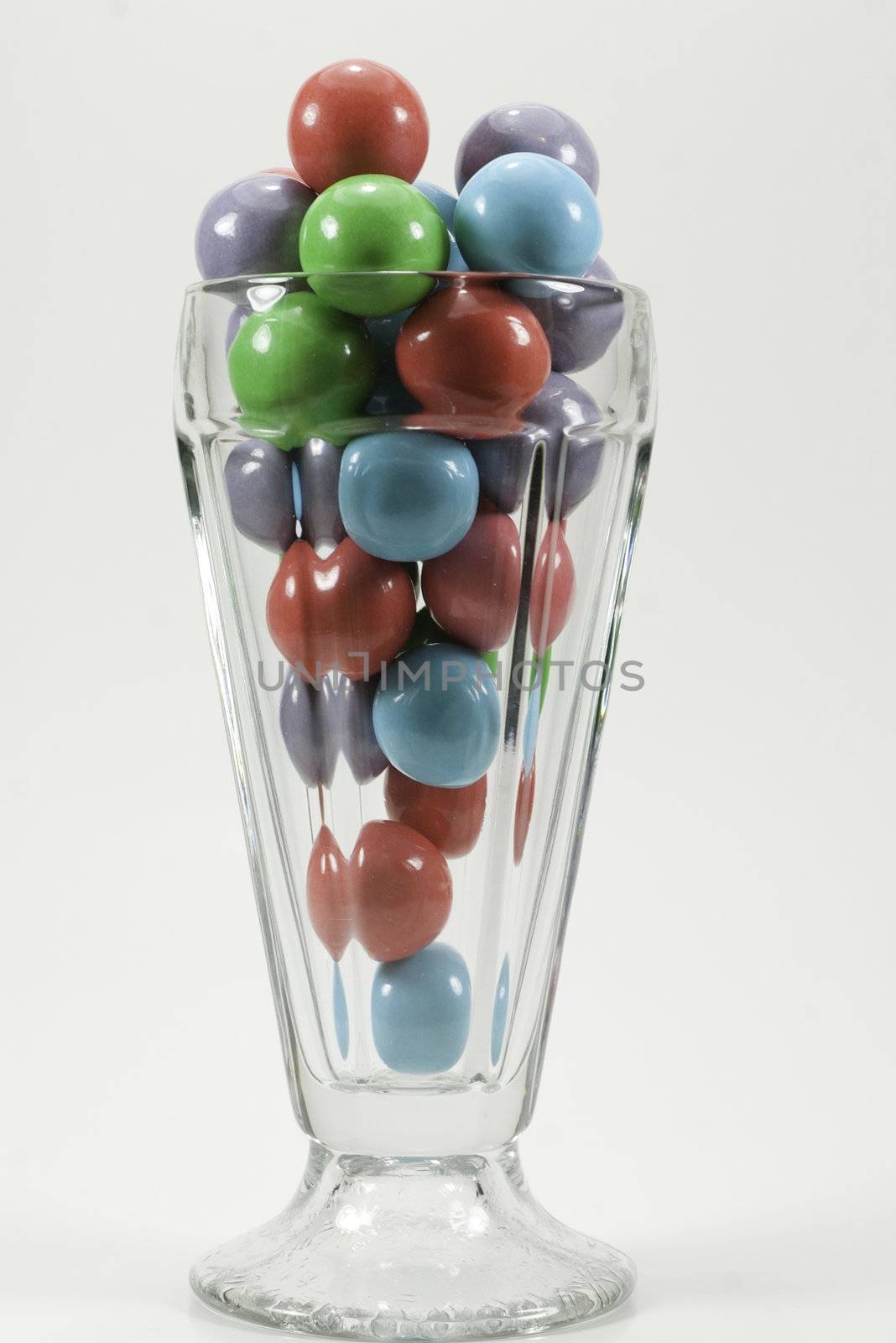 a sunday glass filled with colorful red, green, blue, and purple gumballs