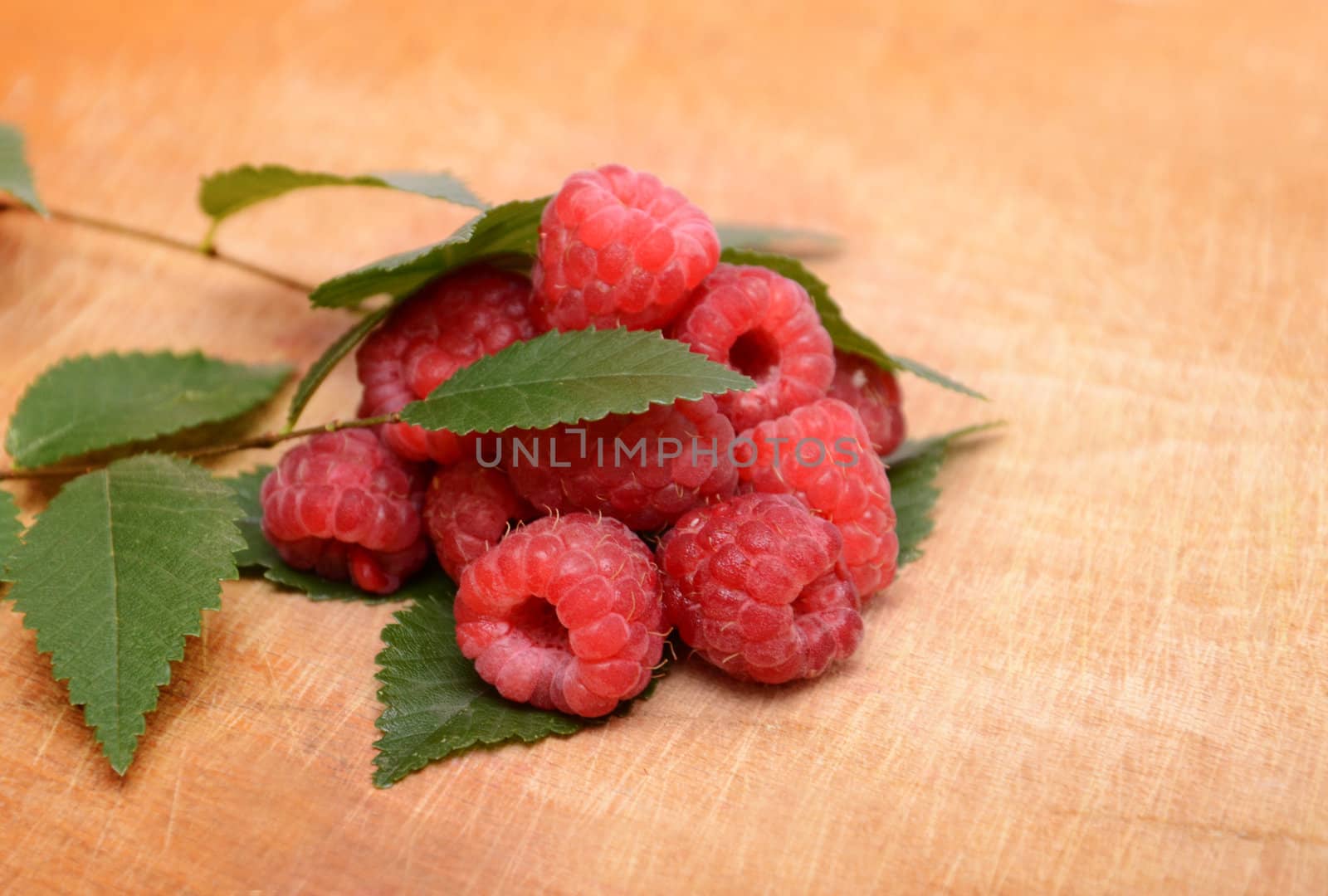 heap of ripe raspberries with leaves 