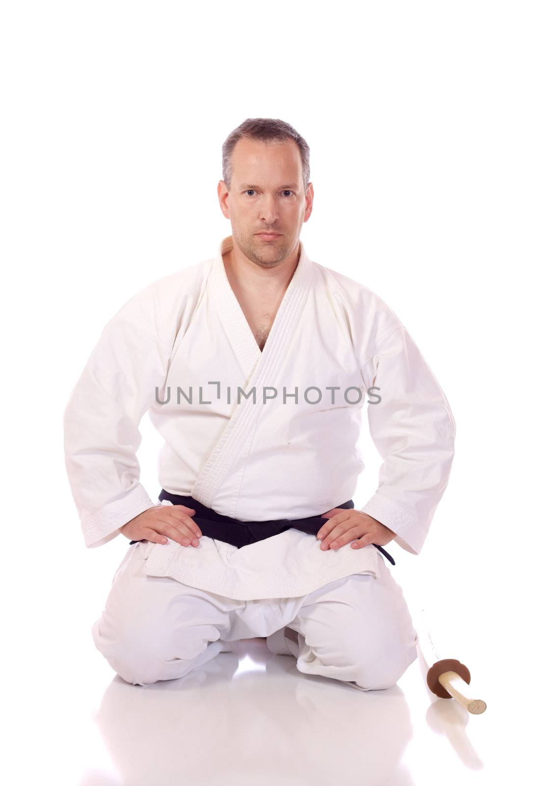Man in karate-gi holding a boken in the seiza position