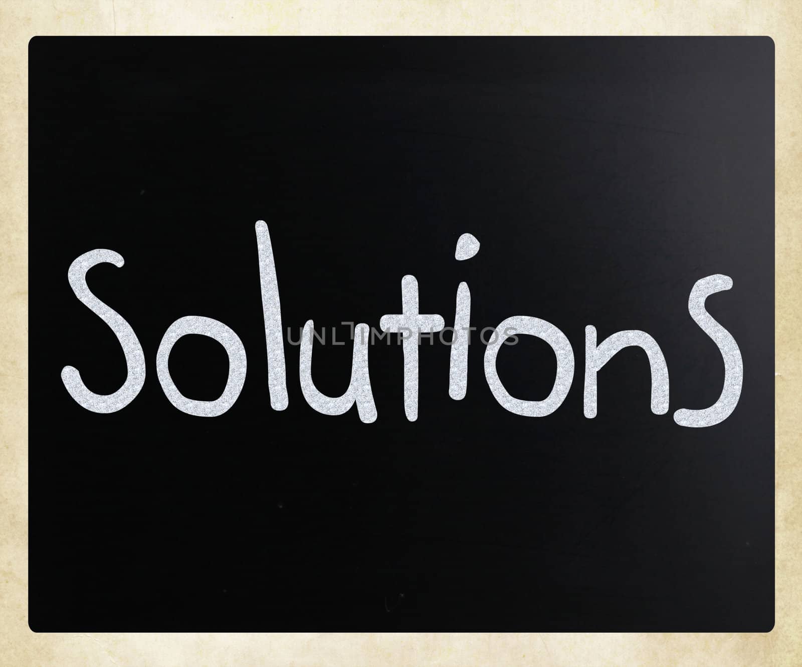 "Solutions" handwritten with white chalk on a blackboard