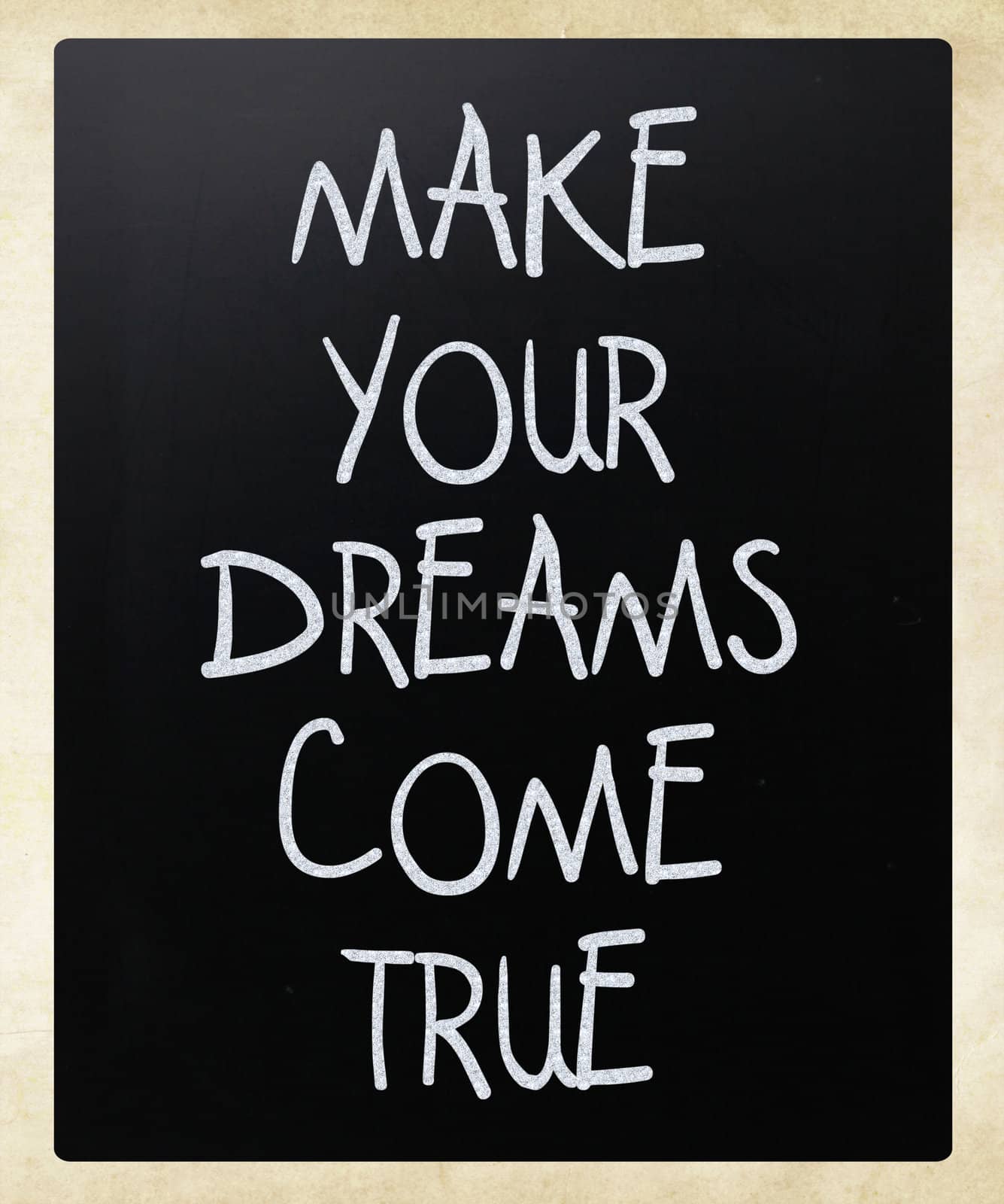 "Make your dreams come true" handwritten with white chalk on a blackboard