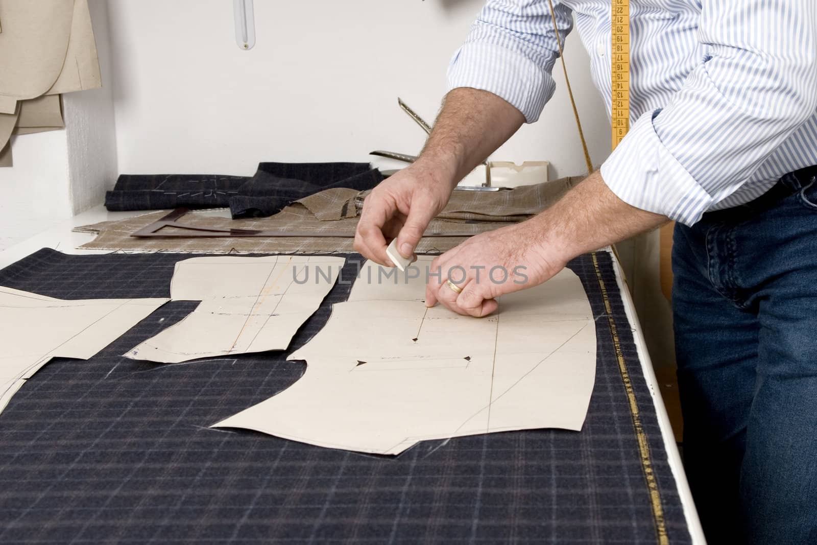 Tailor at work, drawing line on fabric with chalk