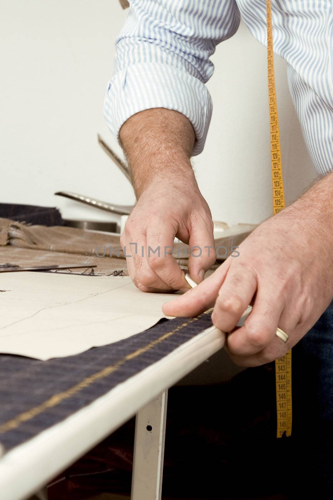 Tailor at work, drawing line on fabric with chalk