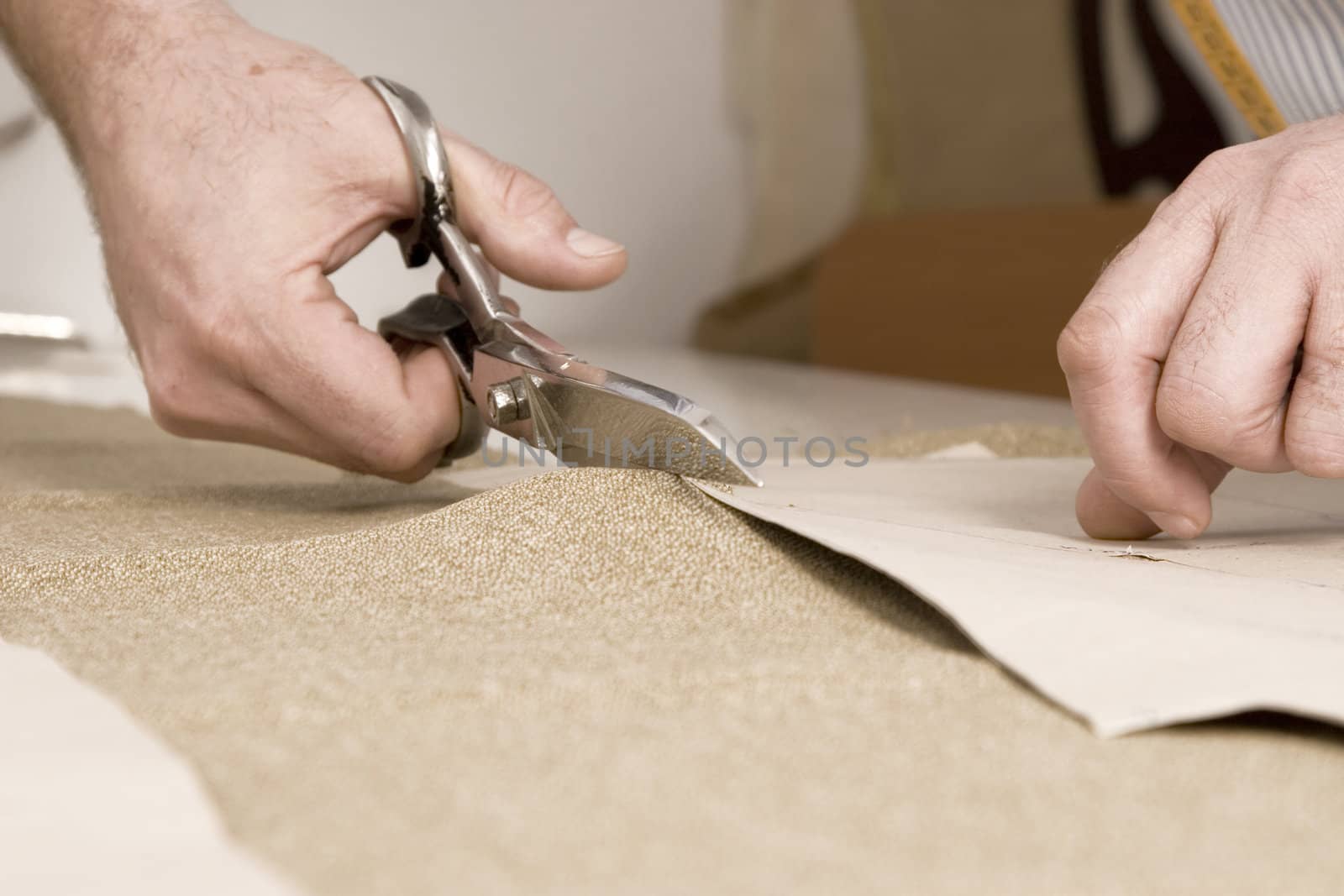 Tailor working at studio cutting fabric, detail of hand with scissors