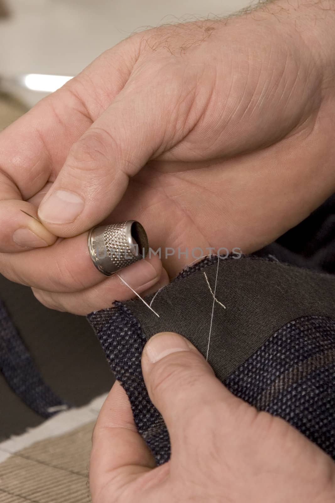 detail of sewing hand in tailor studio
