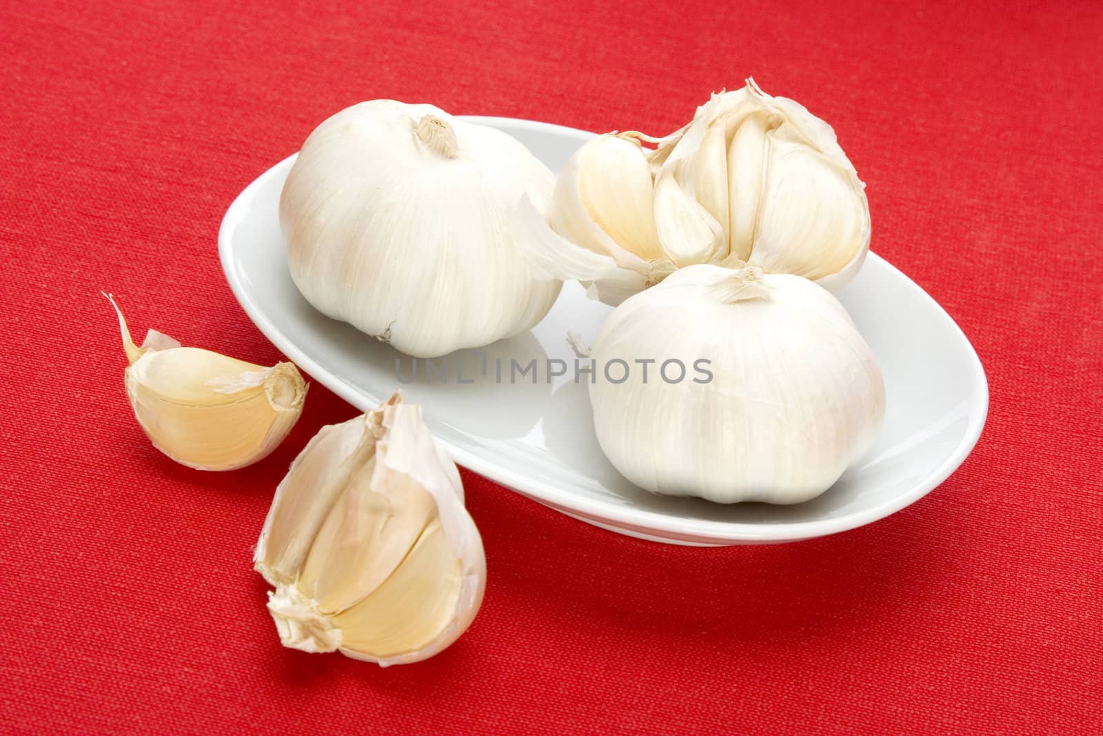 garlic in white bowl over red fabric background