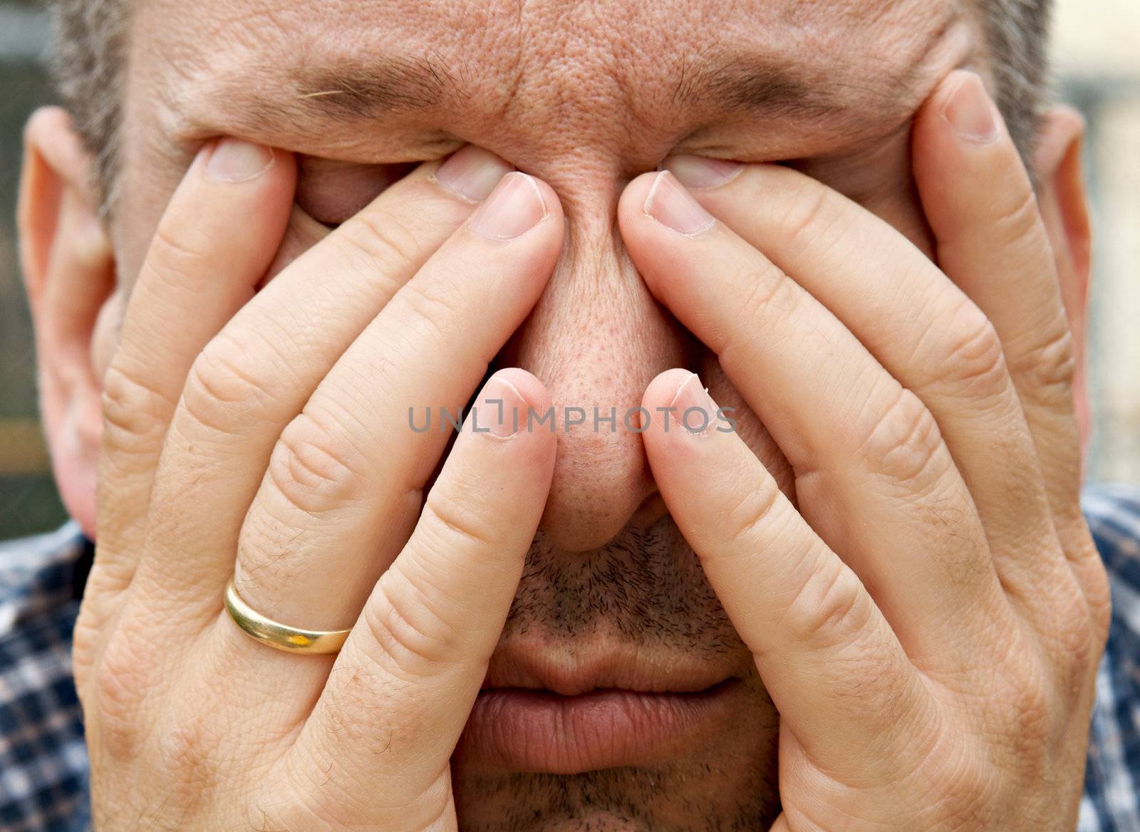 Man with his hands in his face looking tired