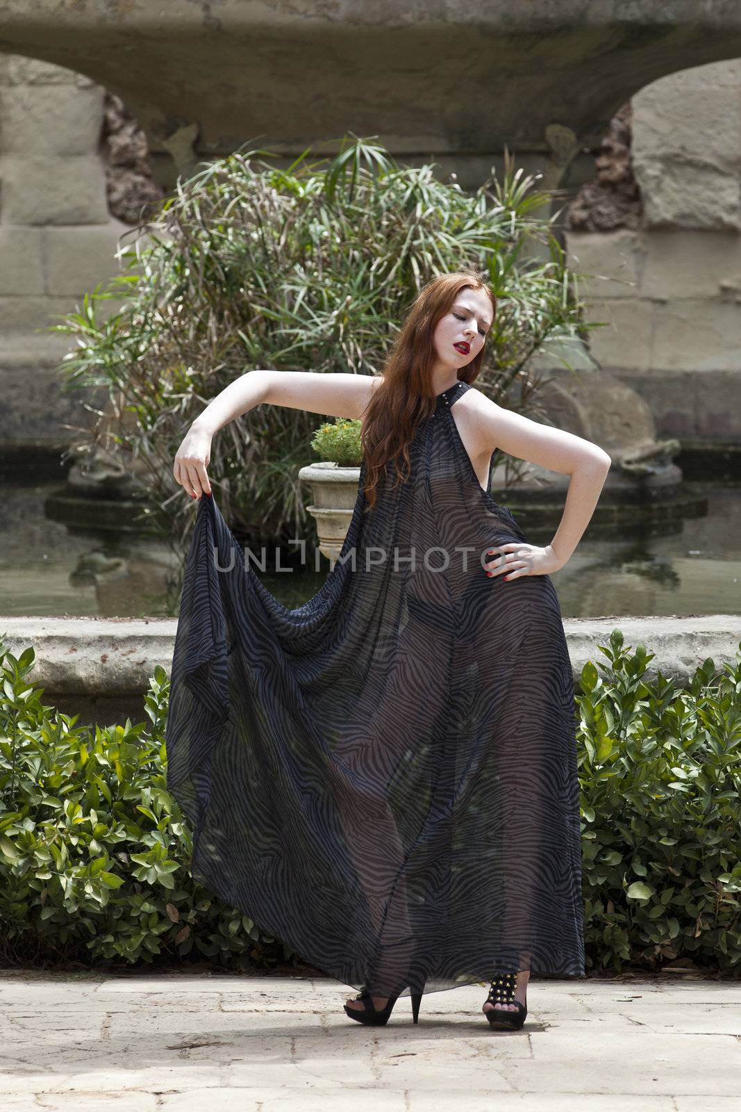 A beautiful young woman in a transparent dress in a garden