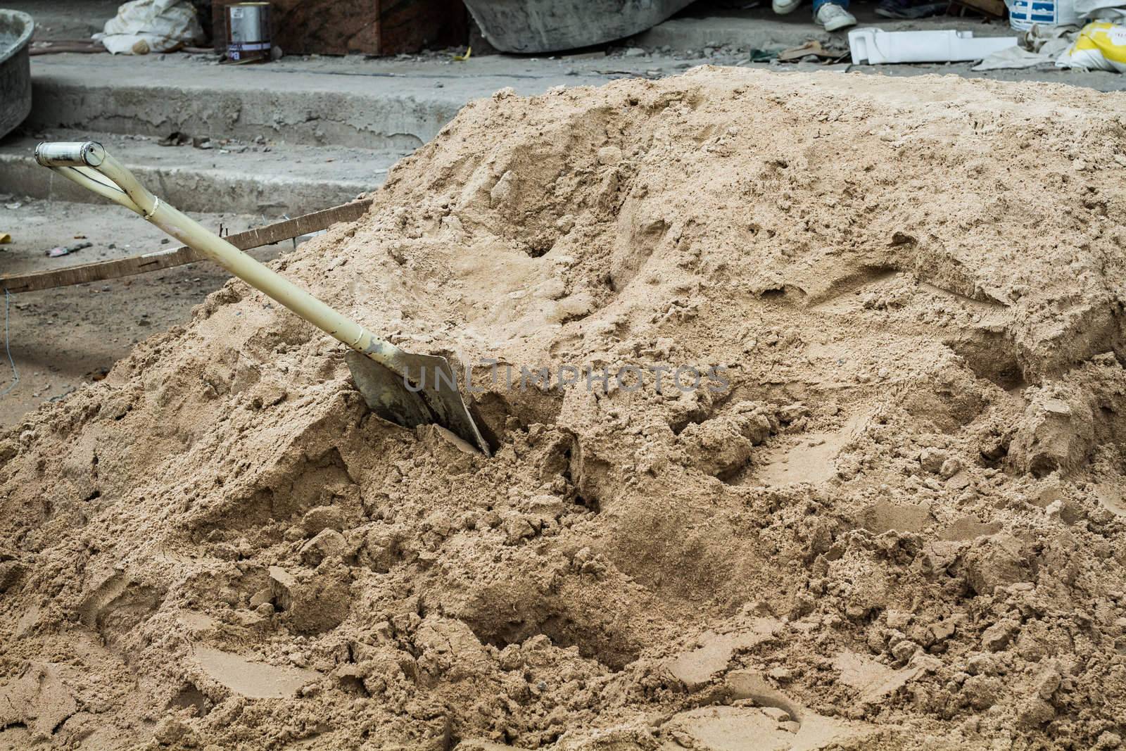 a shovel digging into pile of building sand