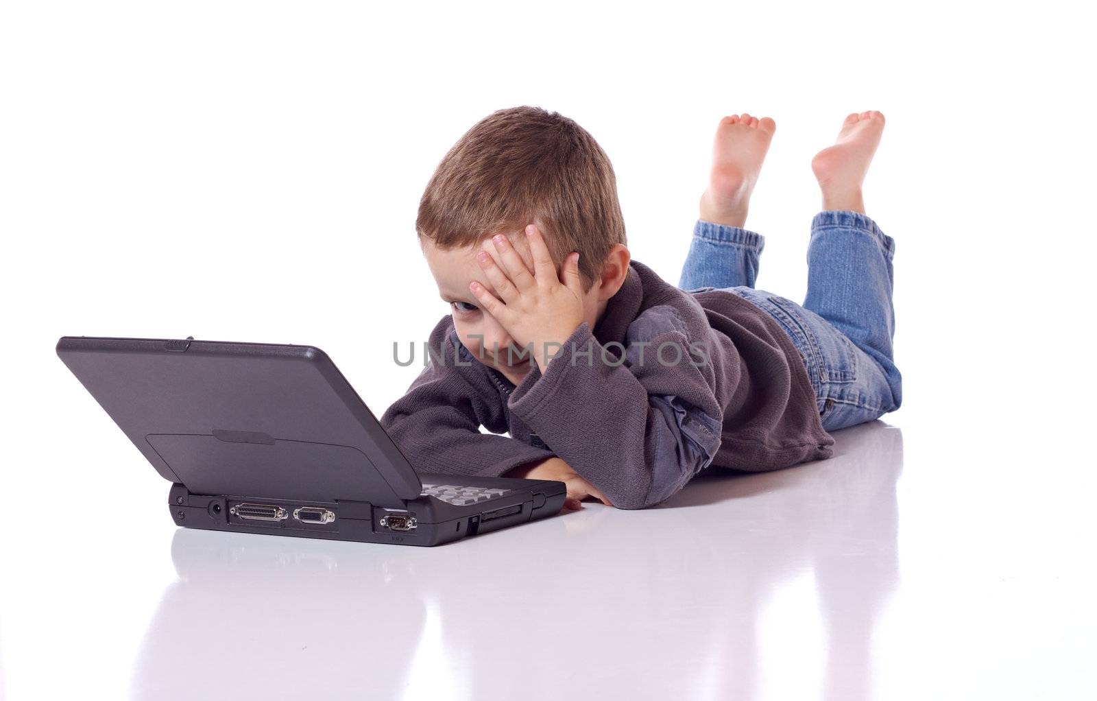 Cute little boy laying on his stomach with a laptop