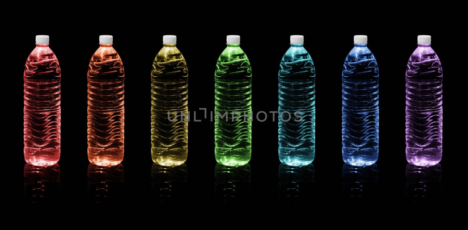 Seven bottles of drinking water colors of the rainbow on a black background