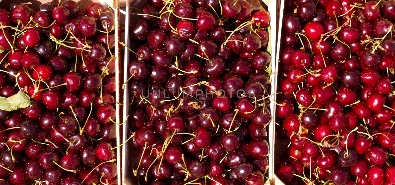 Cherry red fruits in wooden baskets by lunamarina