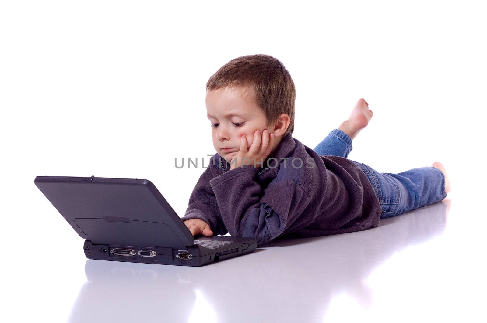 Cute little boy laying on his stomach with a laptop