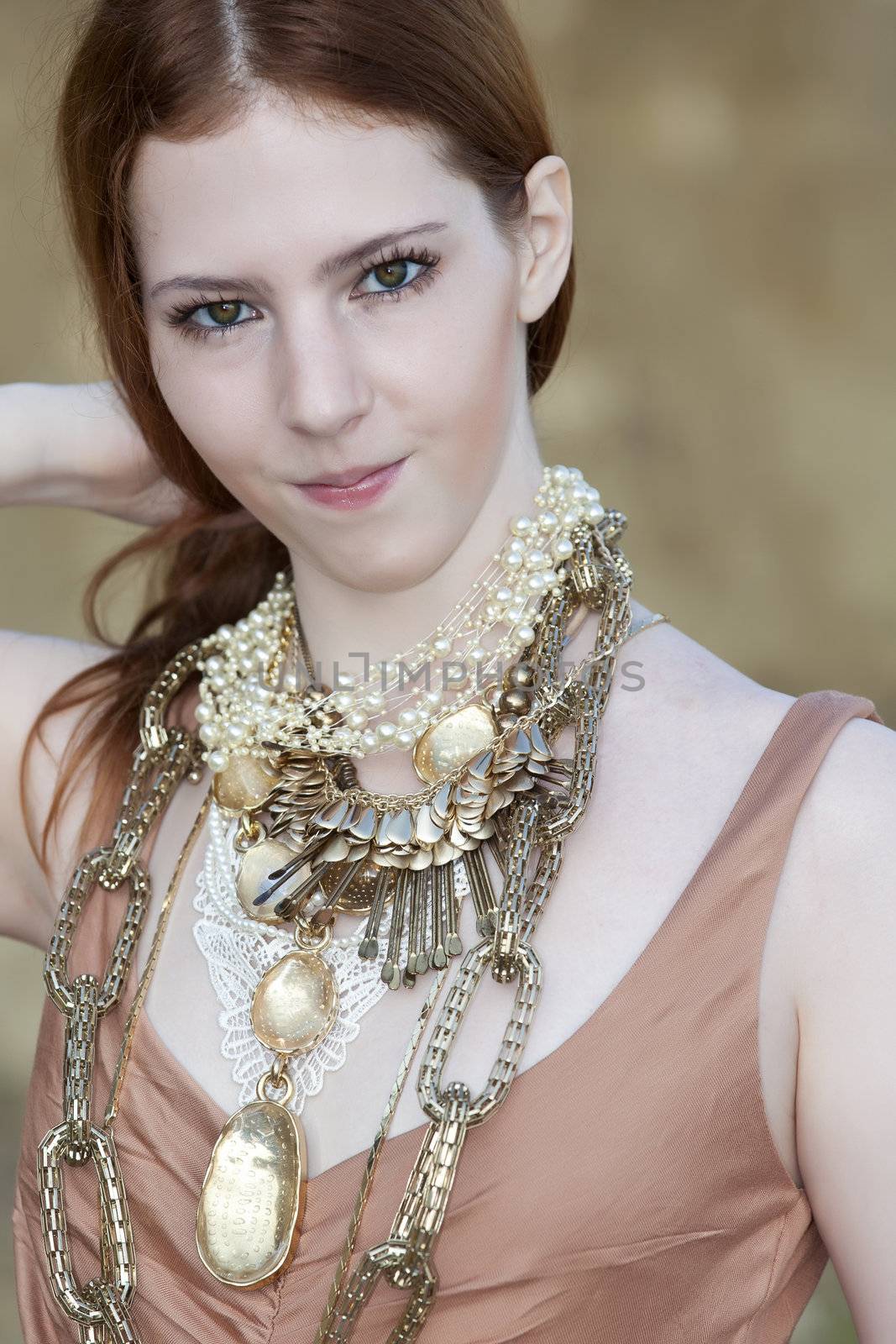 A young woman with beautiful milky skin and red hair wearing Bohemian jewellery