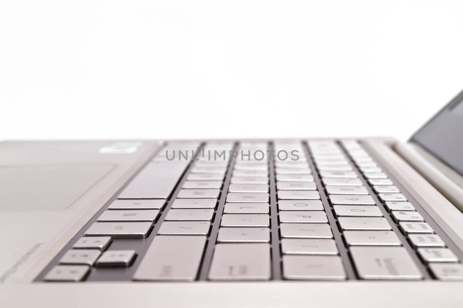 Angled view of a keyboardpad on a modern metal-finished laptop against white for abstract and background