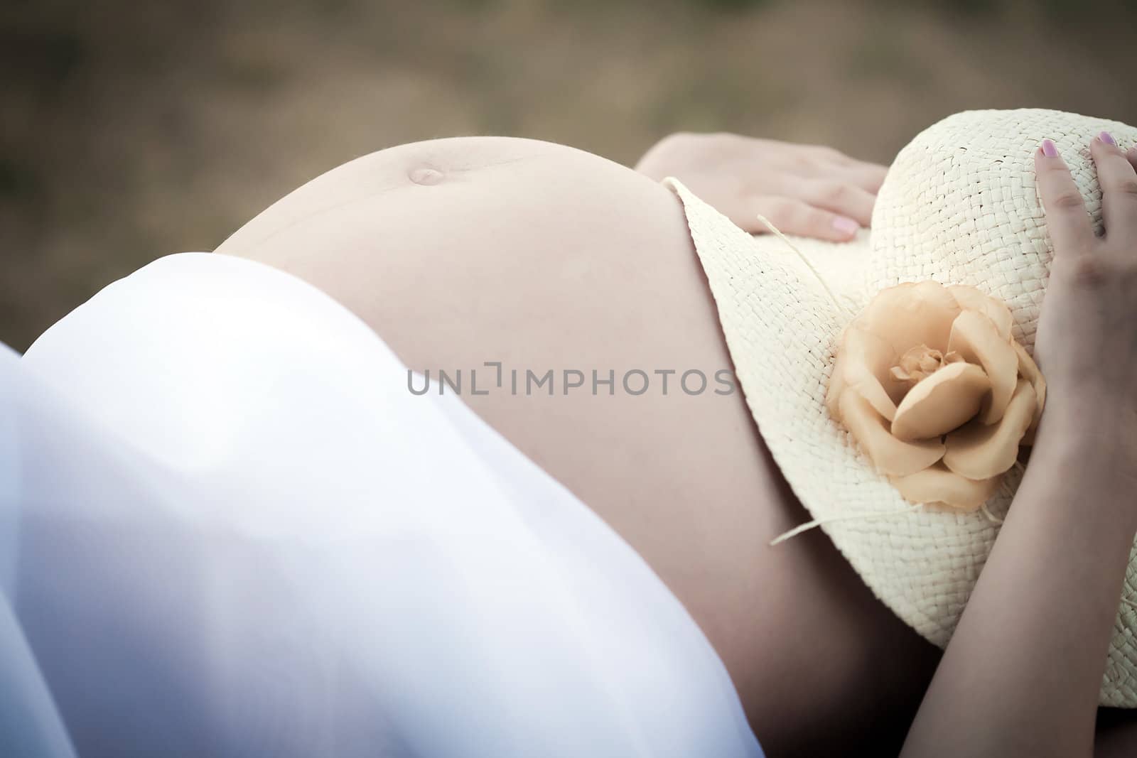 Pregnant woman holding a hat on her belly