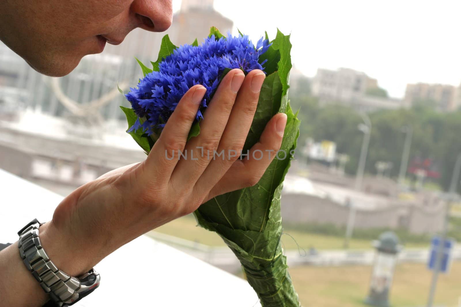 The man holds a bouquet from cornflowers on a background of city