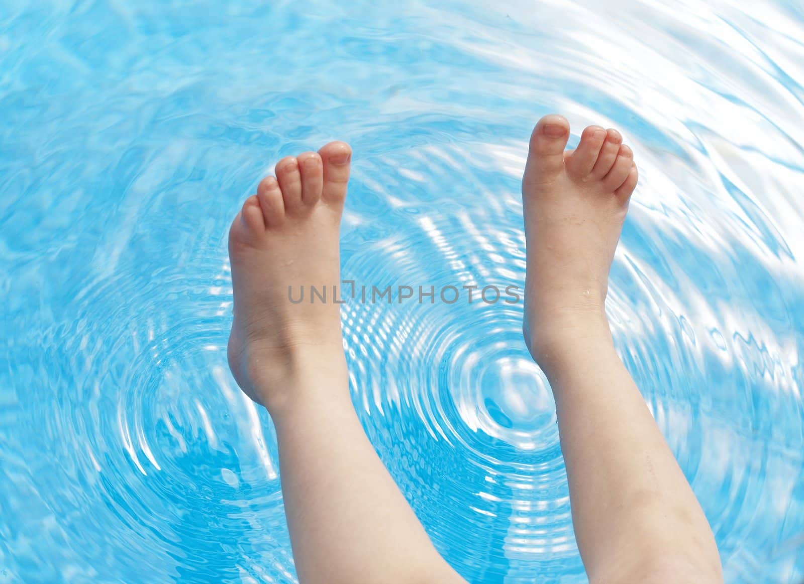 a young kids feet over blue pool water