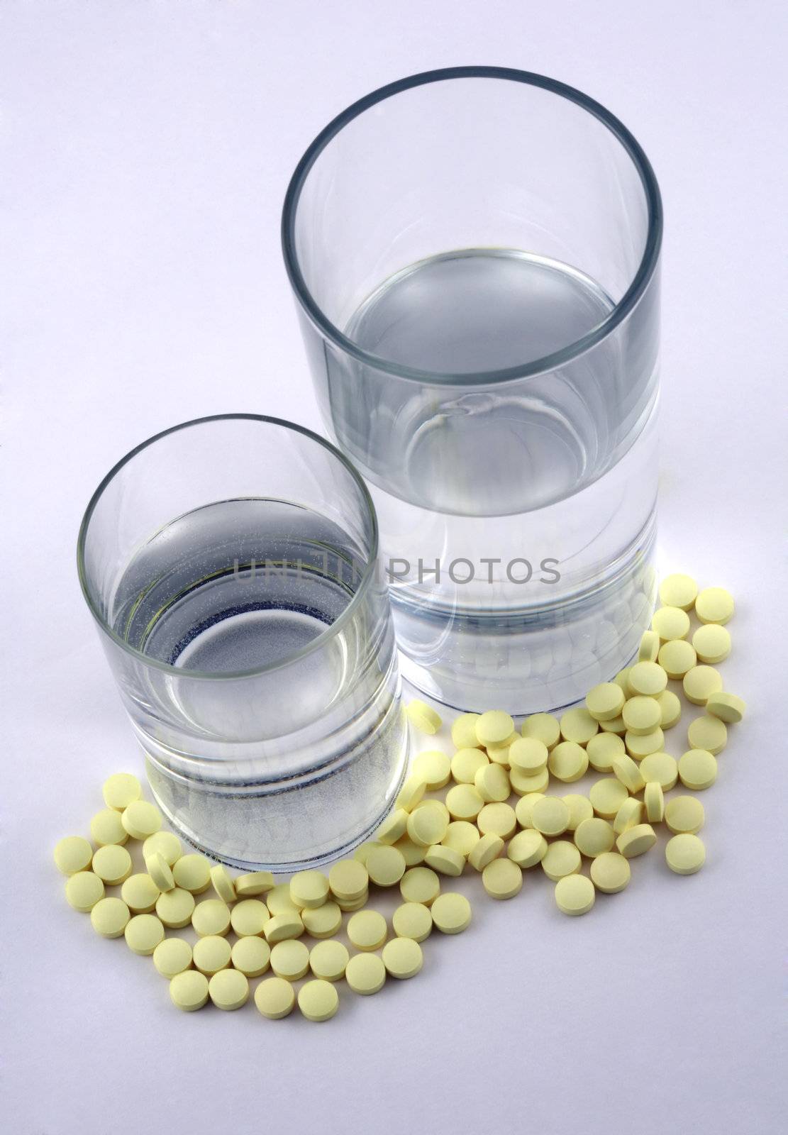 Many yellow tablets and two glasses with water