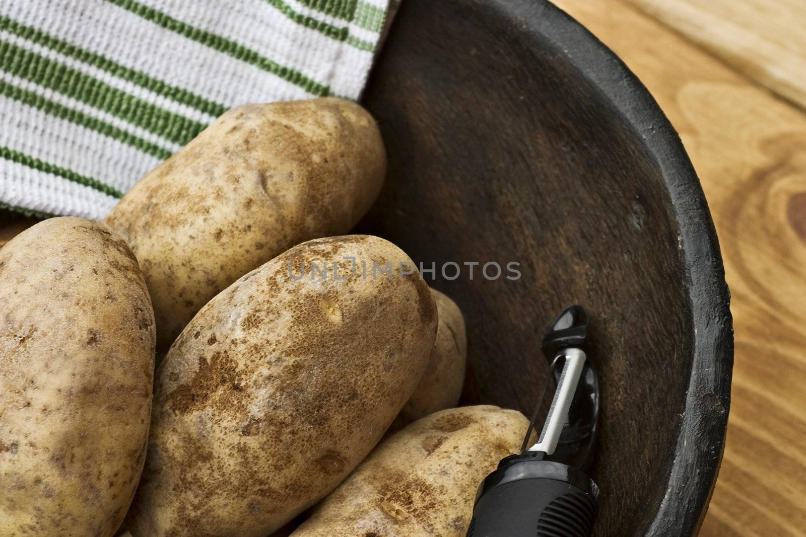 Potatoes in a hand carved wooden bowl with kitchen towel.
