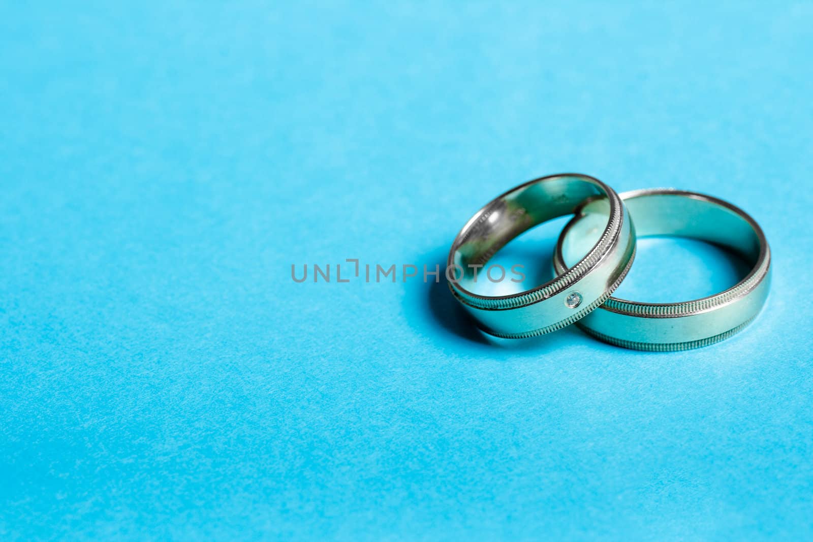 Pair of wedding bands isolated on blue background, macro