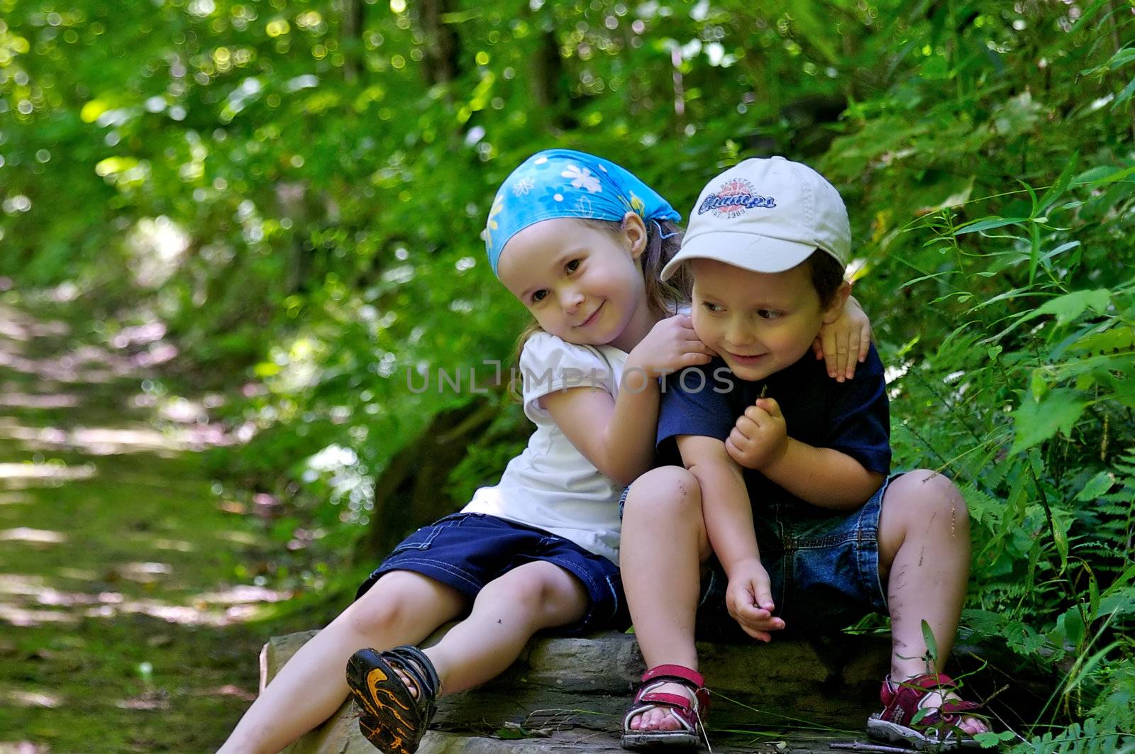 Brother and sister sitting on a rock in a beautiful trail in the woods