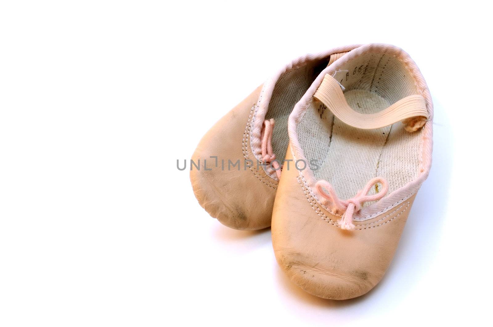 Small pink ballet shoes resting on a white background
