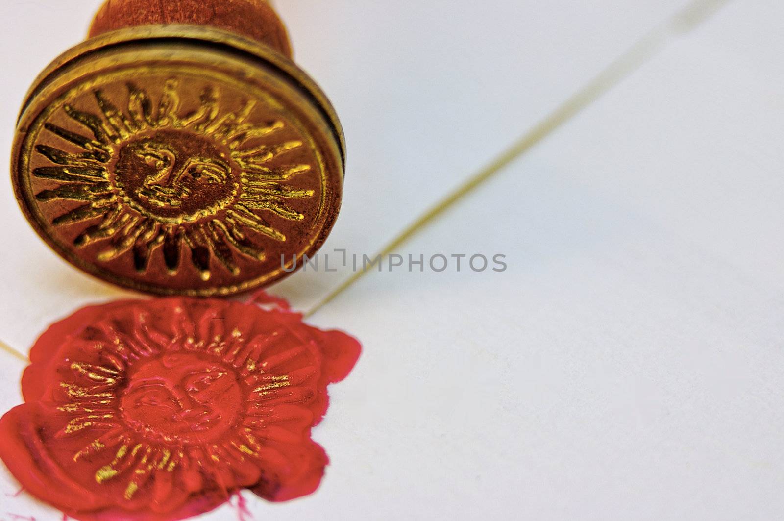 Signet stamped in red wax and gold ink to seal a parchment envelope