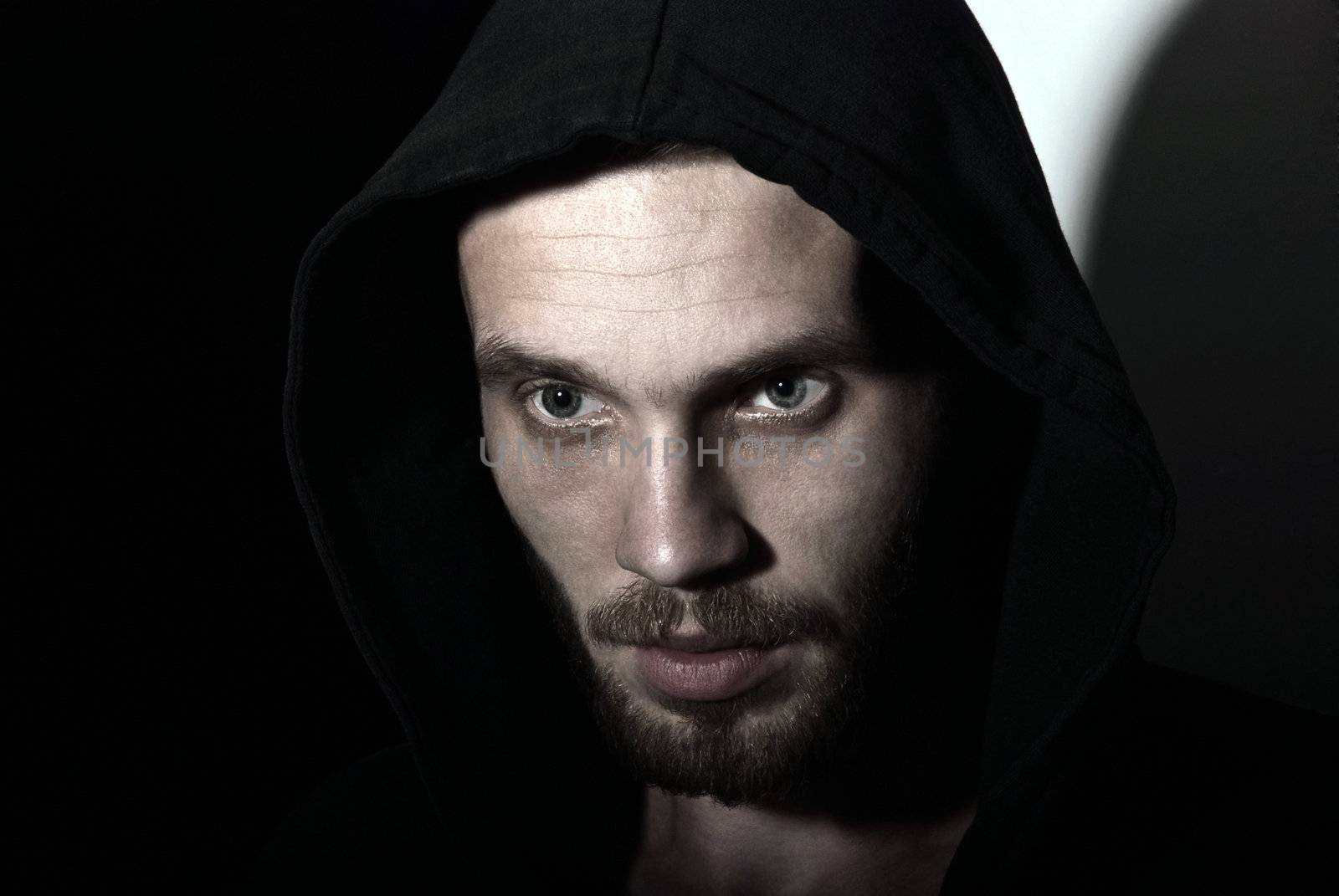Low key strong portrait young man with bristles and evil look.
