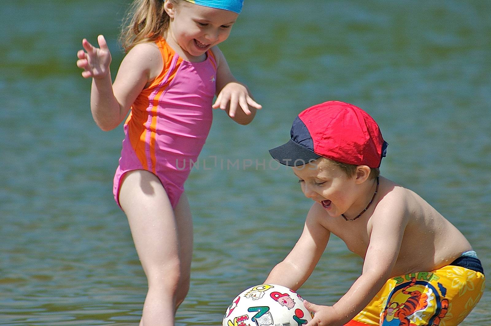 Brother and sister playing with a ball in the water