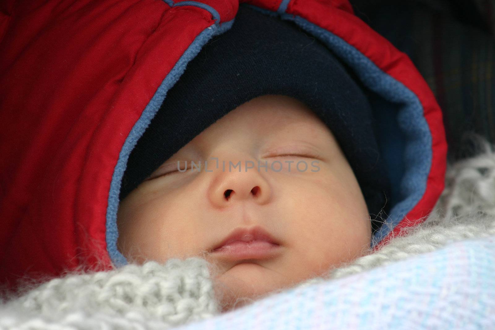 Little baby sleeping outside in his stroller on a winter day