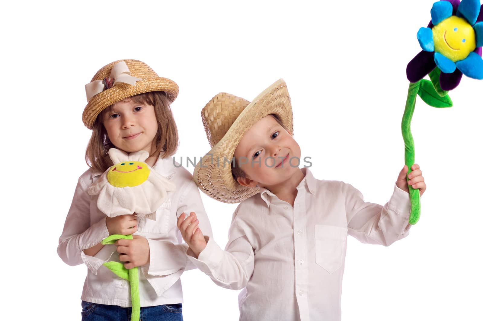 Cute little brother and sister playing with hats and flowers