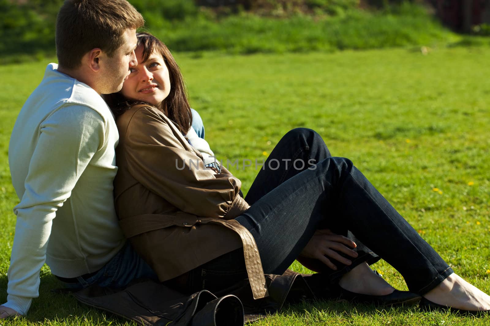 young couple sitting on the green grass