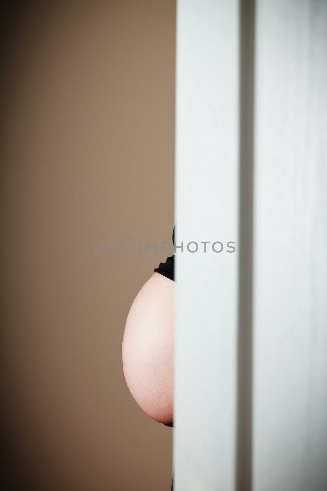Belly of a 32 weeks pregnant woman in front of a door