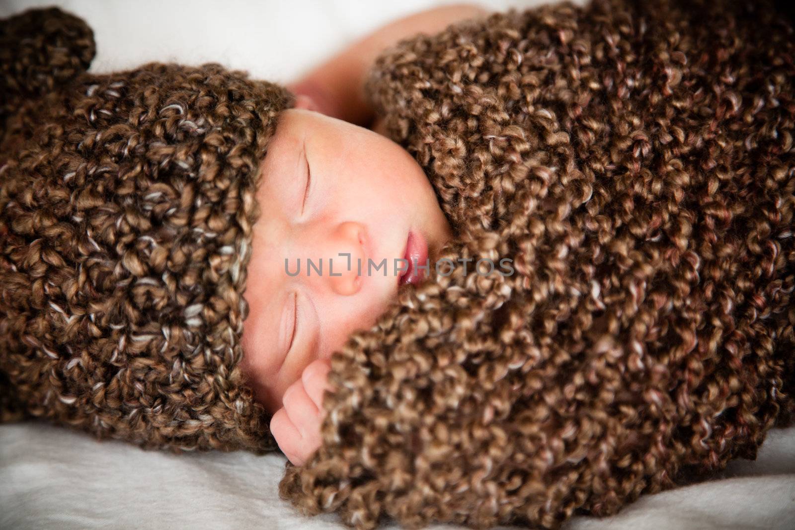 Newborn baby boy resting in a wool cocoon