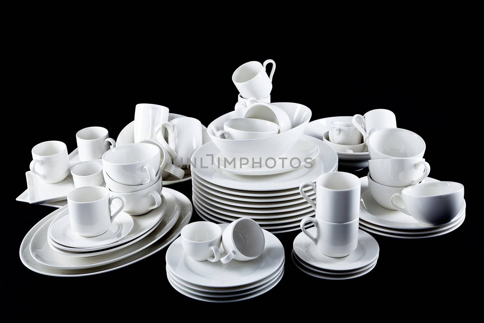 stack of mixed white dishes cups and plates isolated on black background
