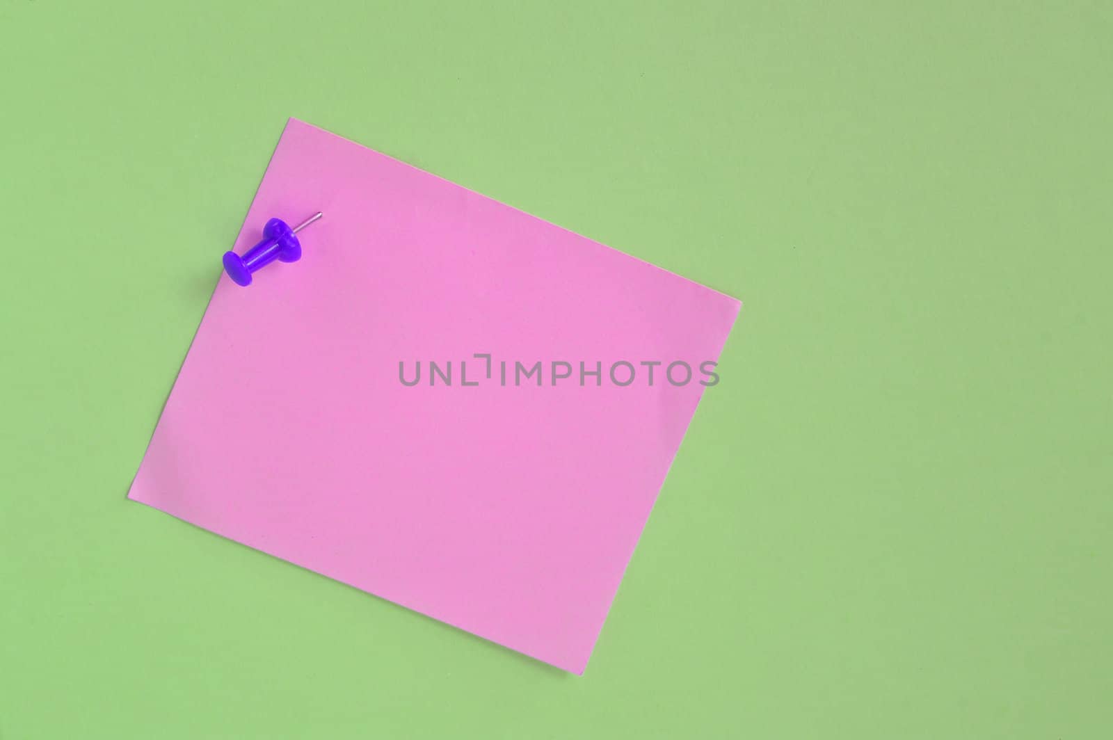 pink note paper with pin on green background