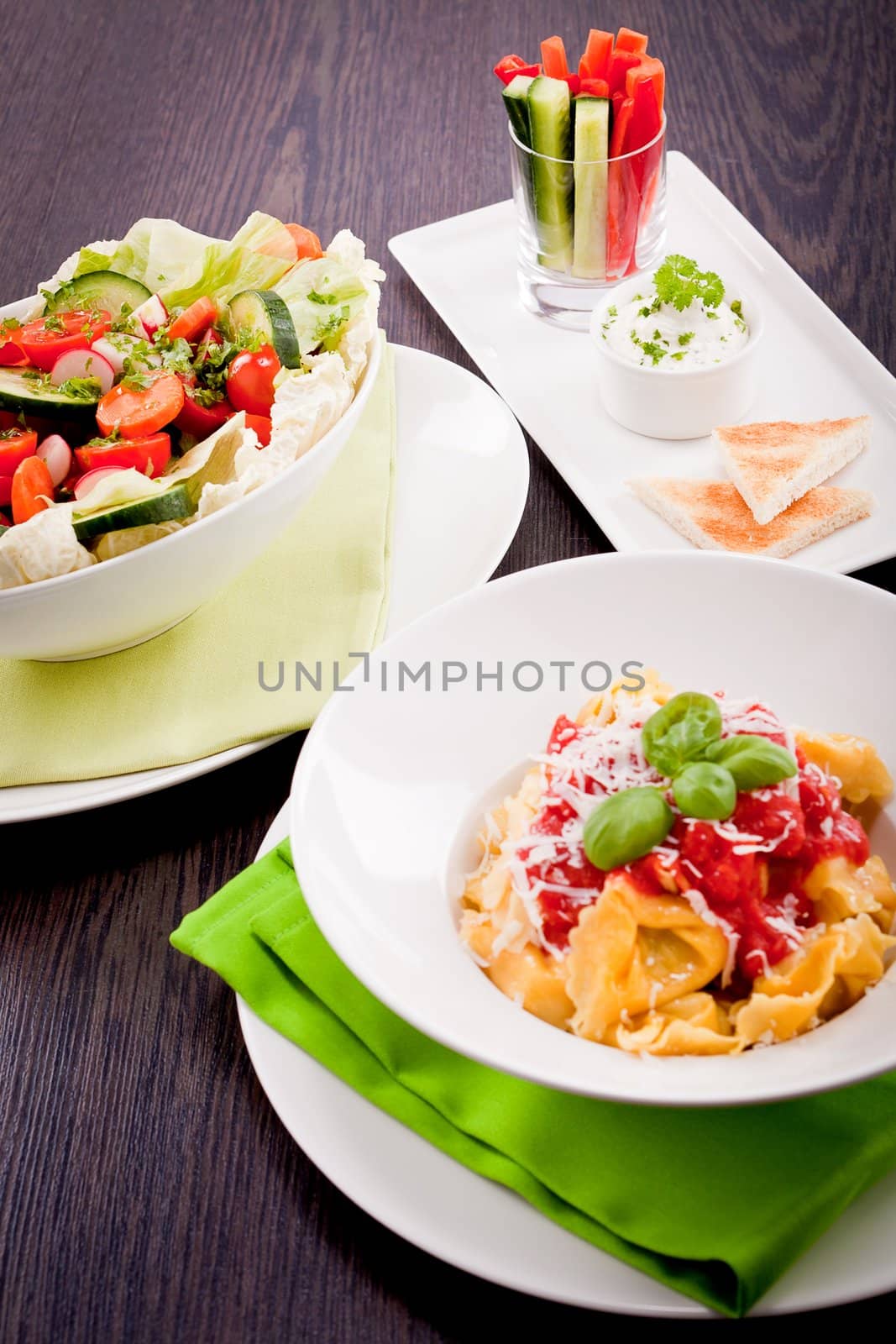 collection of different plates with healthy food pasta salad vegetables on wooden table