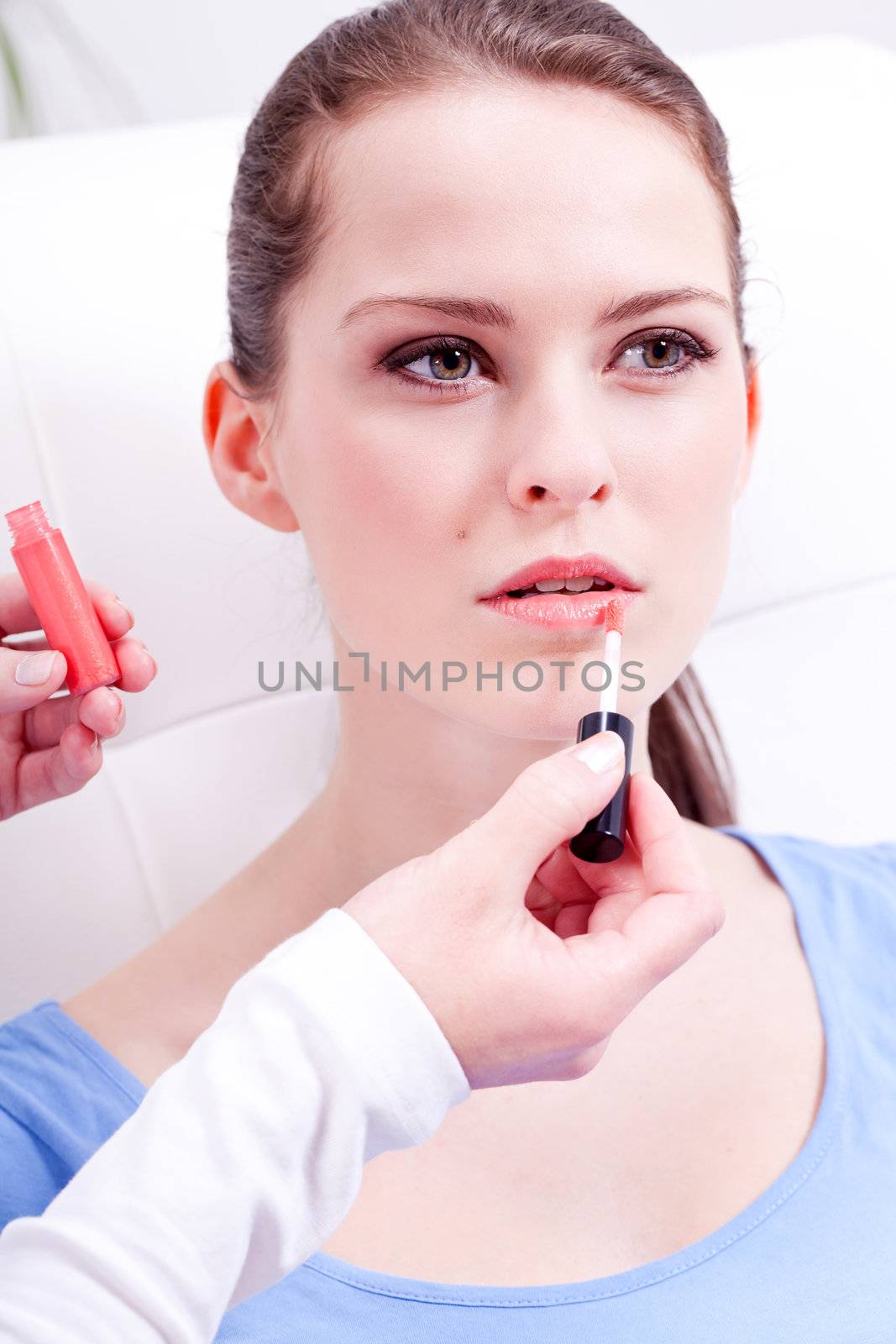 brunette attractive woman portrait applying lipstick lipgloss in beauty salon