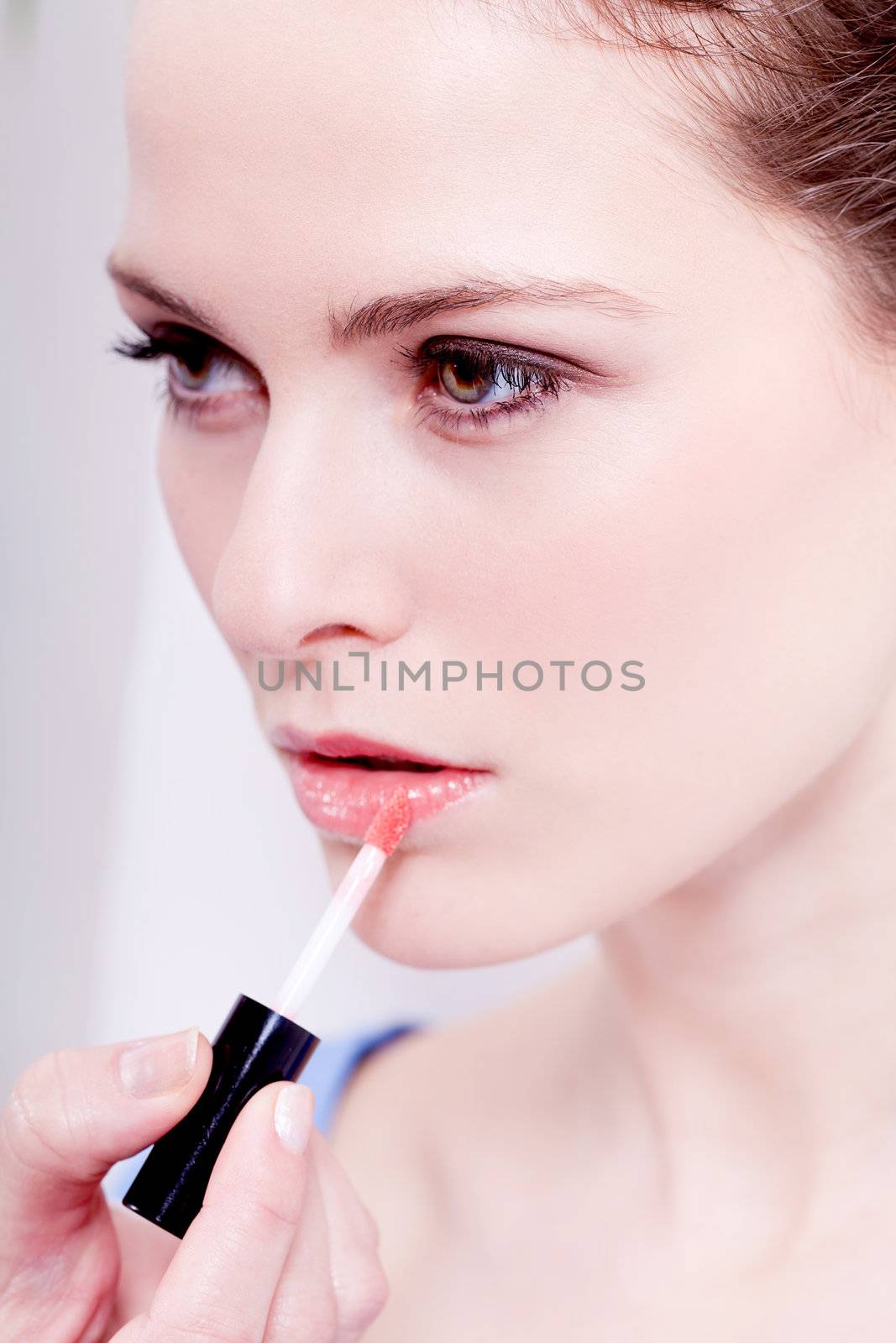 brunette attractive woman portrait applying lipstick lipgloss in beauty salon