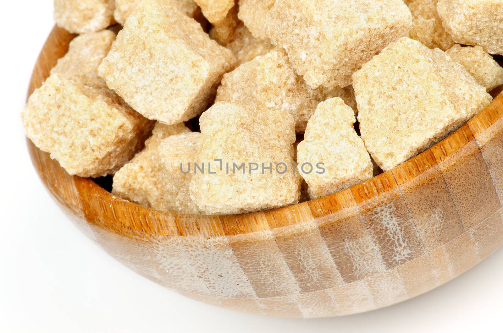 Cubes of Brown Cane-Sugar in Wood Bowl closeup on white background