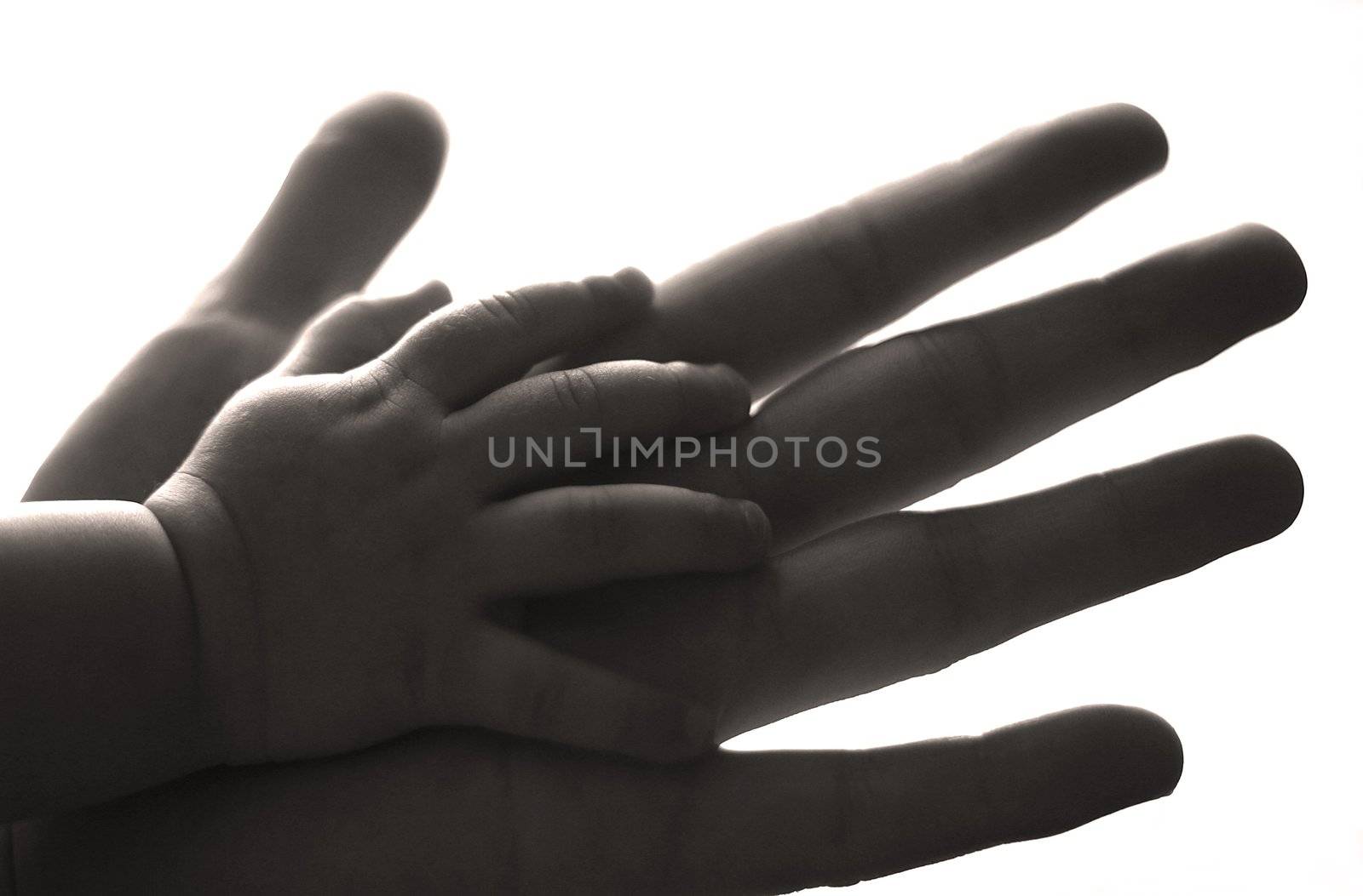 The image of hands of parents and the kid. b/w+sepia