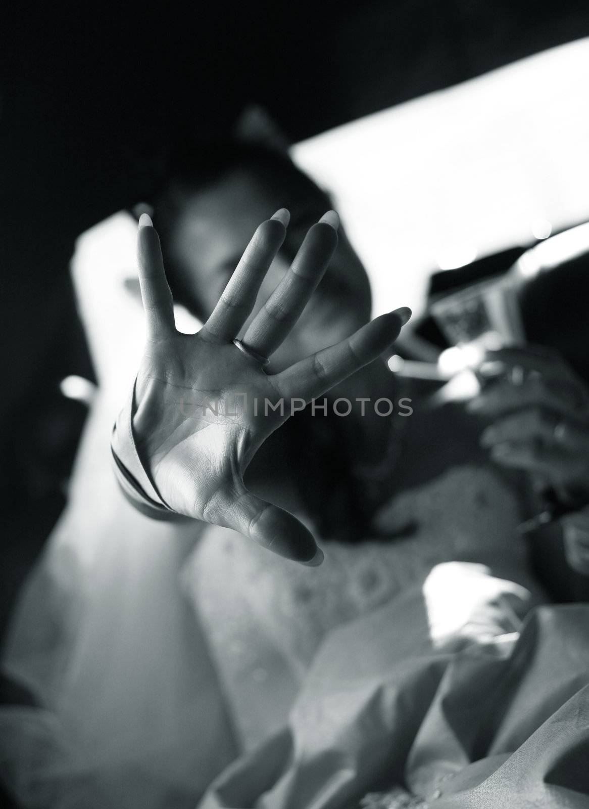 The bride is closed from the photographer by a hand. b/w