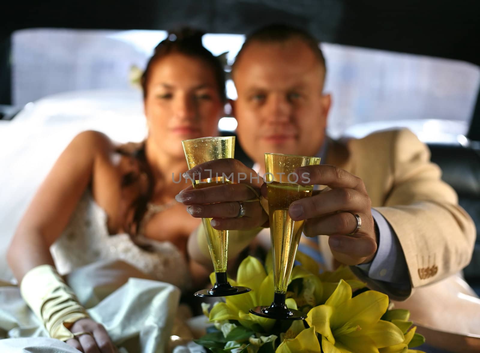 Glass of champagne in a hand of the groom and bride
