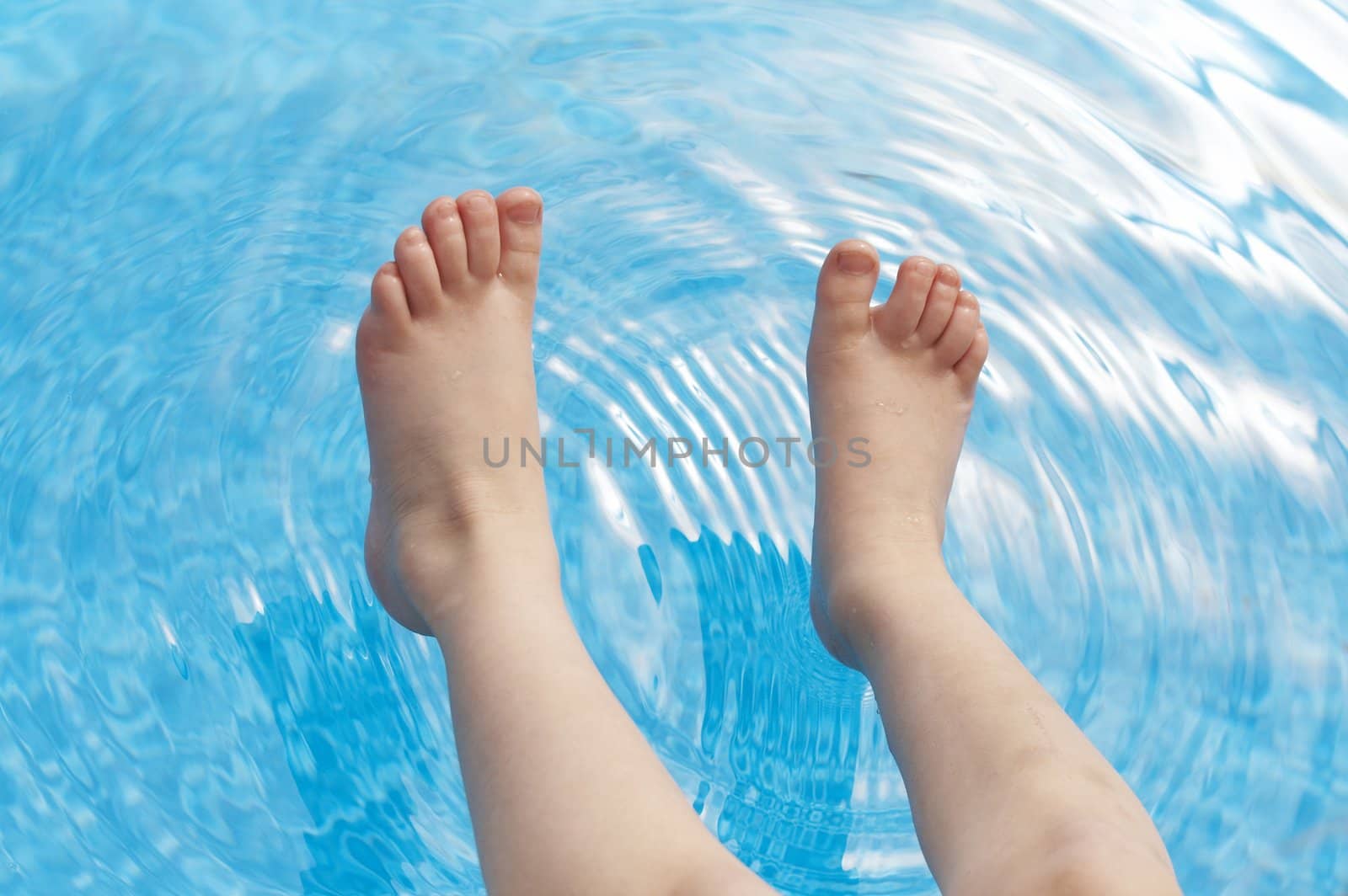 a young kids feet over blue pool water