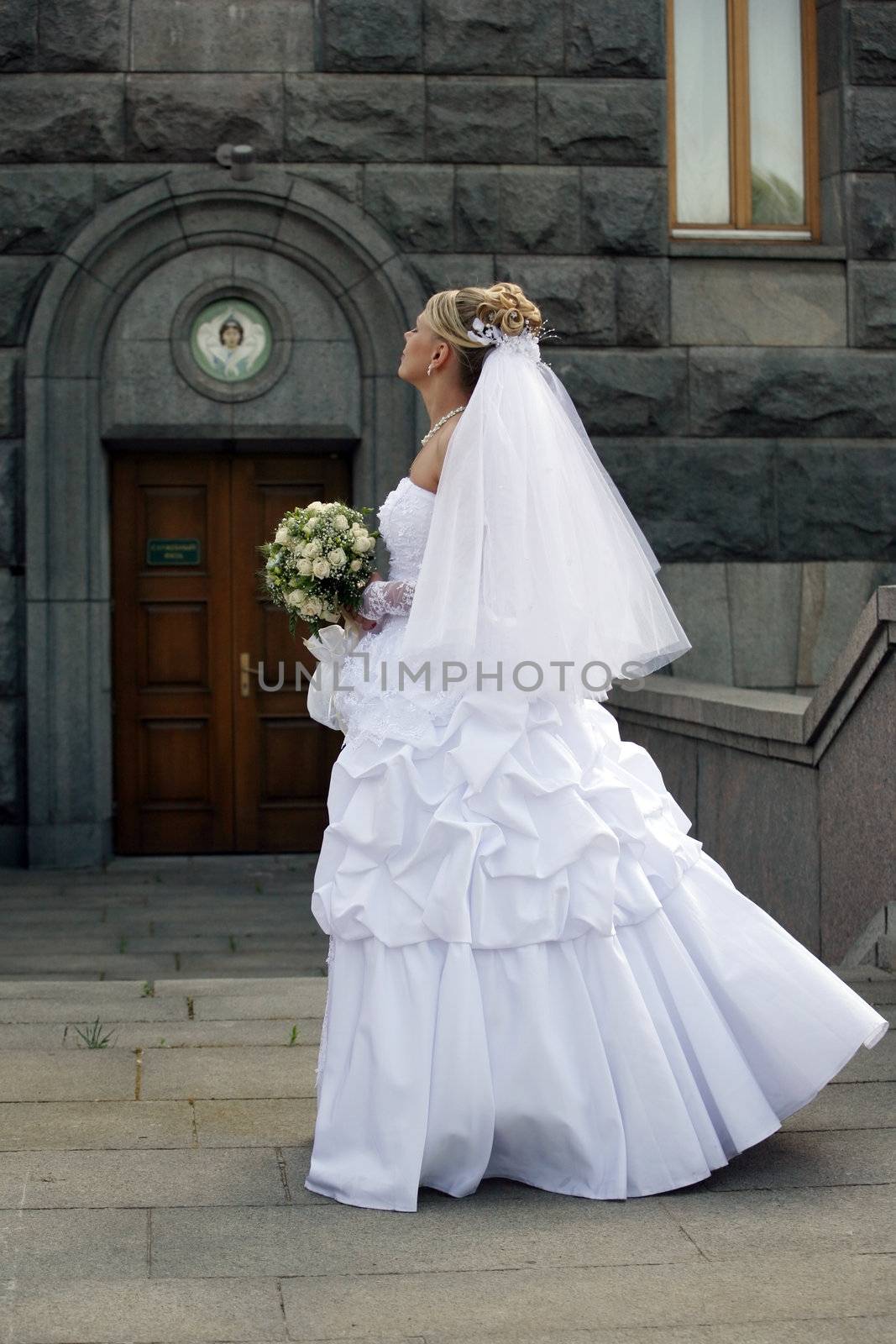 The beautiful bride with a bouquet on a background of church