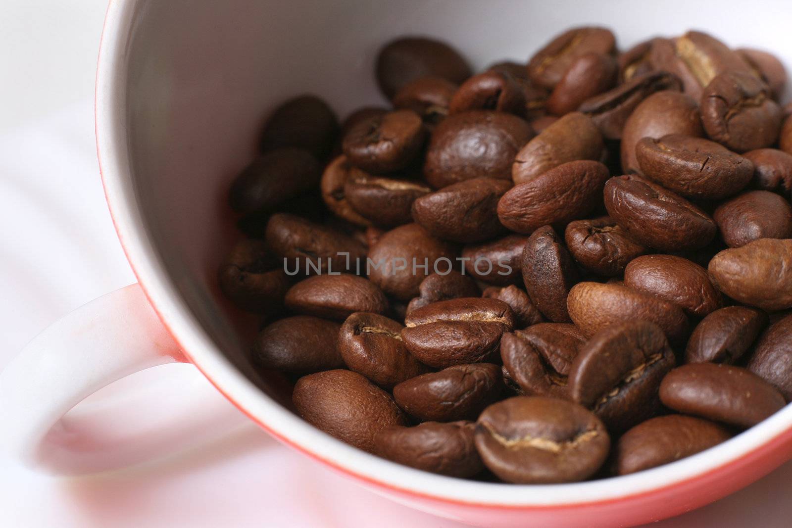 Grains of coffee in a white bowl. Macro-ring