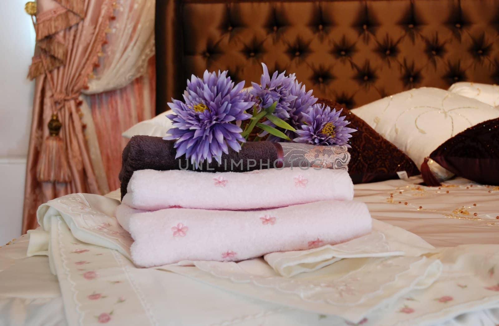 Folded towels ready for use set out on a hotel room bed.