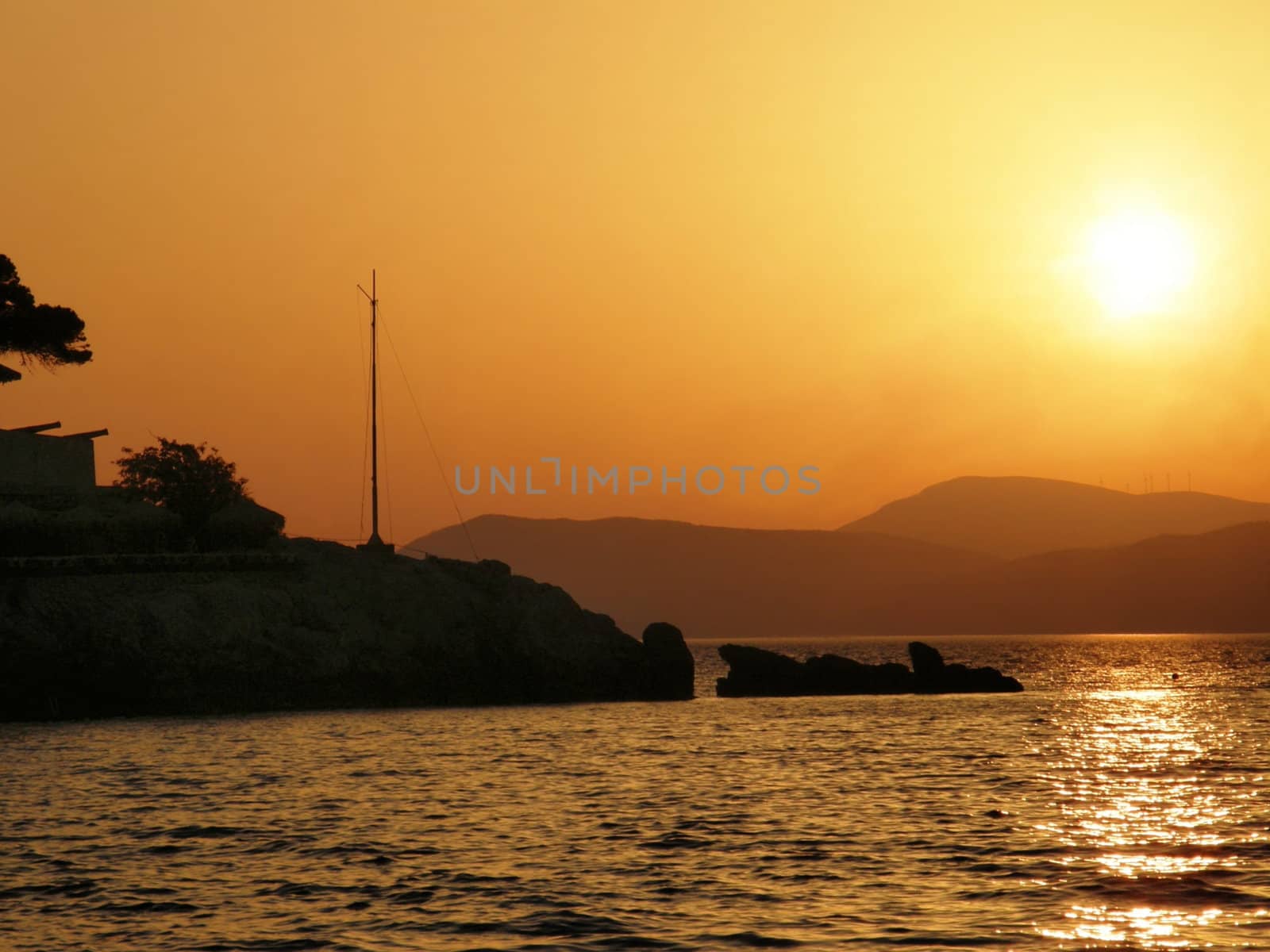 a beautiful sunset over an island with mountains as a background