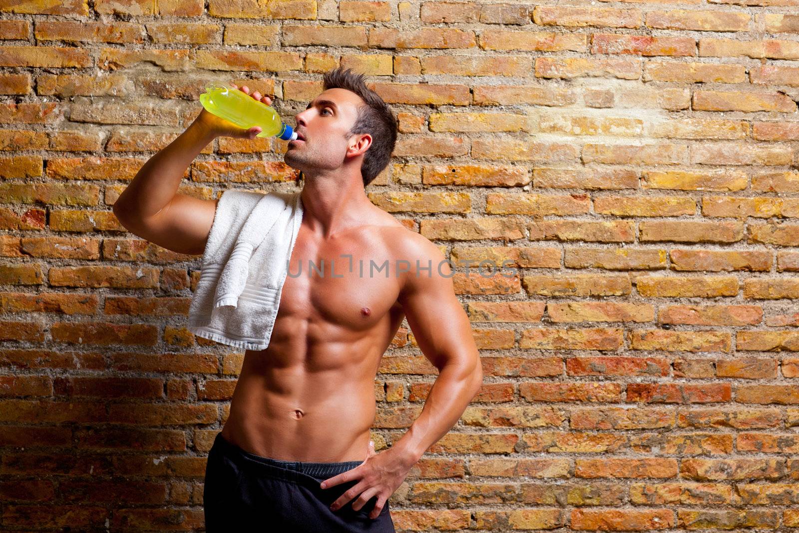 muscle shaped man at gym relaxed drinking energy drink